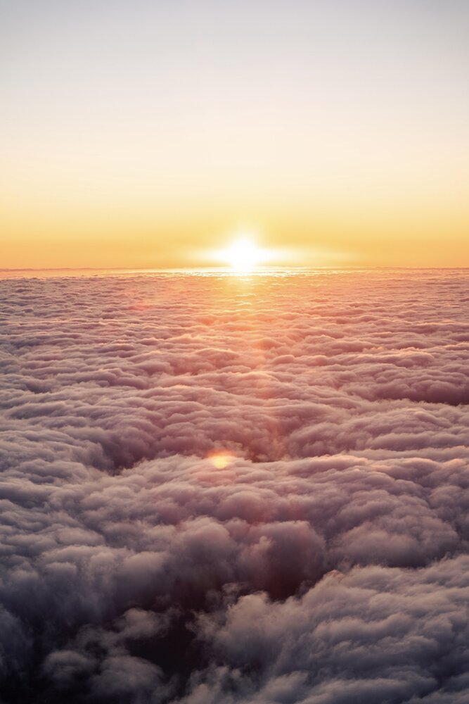 Sun setting over a sea of clouds seen from altitude